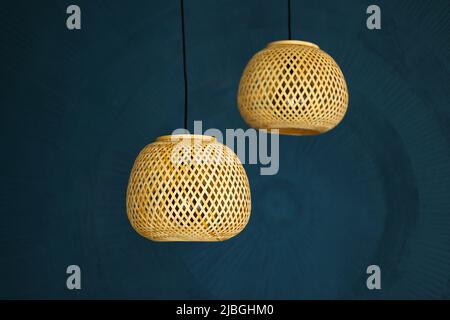 two rattan chandeliers on blue wall background. Straw lampshade in modern living room. Eco-friendly interior design using natural materials. Scandinav Stock Photo