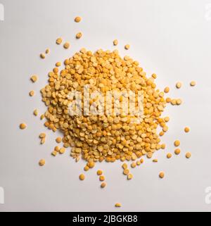 heap of yellow split peas, dried, peeled and split seeds of pea, isolated on neutral gray background, taken from above Stock Photo