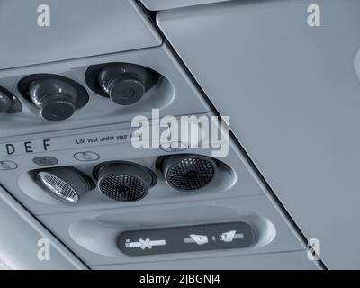 The close up of air conditioner system and sign of seatbelt which installed on overhead in airplane. Stock Photo