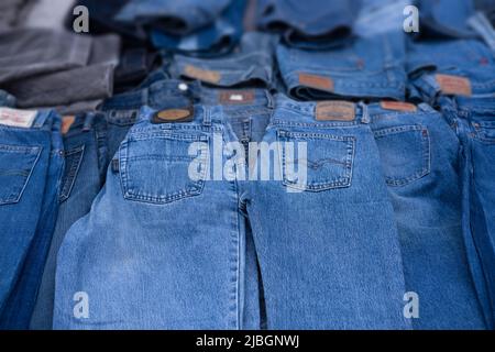 Jeans are displayed in a market stall. Focus on the pockets on the pants, the brands are blurred. Background image Stock Photo