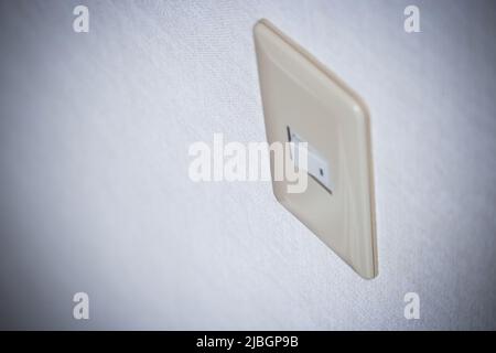 Blurred light switch image which is installed on the white coloured wall from angled view. Stock Photo