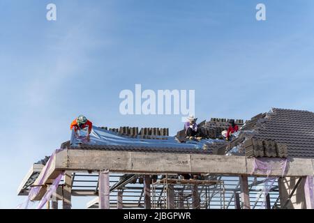 Roofers is installing insulating sheets on a concrete tile roof. Stock Photo