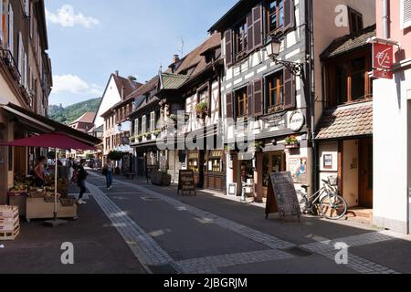 Street with half-timbered houses and shops and people walking in the old French town of Ribeauvillé, Alsace, France Stock Photo