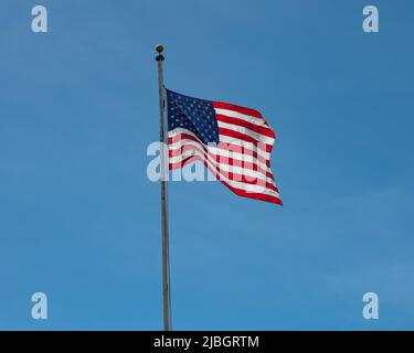 A bright red white and blue American flag waving in a clear blue sky background Stock Photo