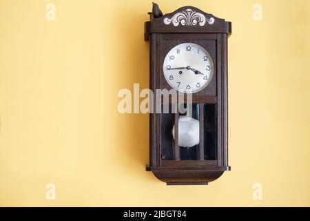 antique wooden grandfather's clock on yellow wall Stock Photo