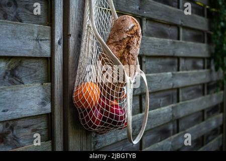String bag with bread and fruits on a wooden background. Stock Photo