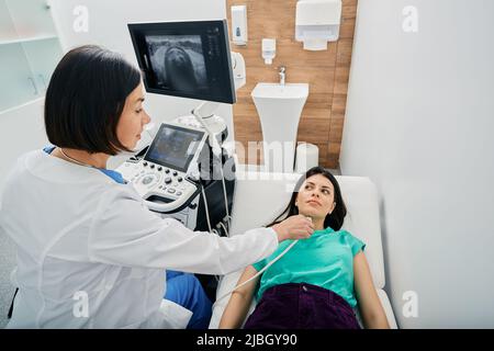 Female patient receives thyroid diagnostics with endocrinologist. Ultrasound diagnostics of endocrine system and human thyroid Stock Photo