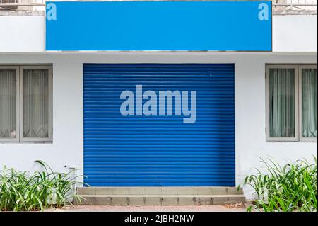 Exterior of closed blue shutter roller door with blank billboard of grocery shop Stock Photo