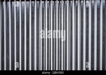 Row of vertical aluminium fence on concrete wall background Stock Photo