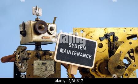 The robot near the mechanism holds a sign system maintenance. Stock Photo
