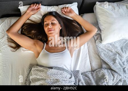 Happy girl waking up stretching arms on the bed in the morning Stock Photo