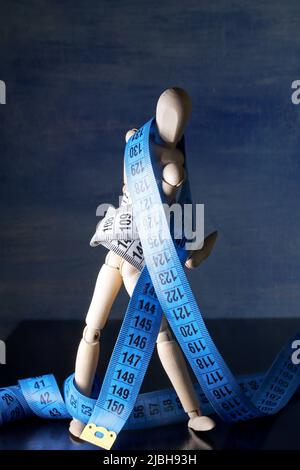 Wooden mannequin with measuring tape Stock Photo