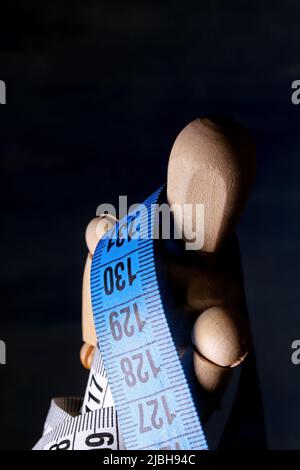 Wooden mannequin with measuring tape Stock Photo