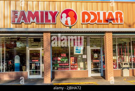 Family Dollar exterior facade brand and logo signage in red, white and orange above glass storefront in the soft light of sunset at a strip mall. Stock Photo