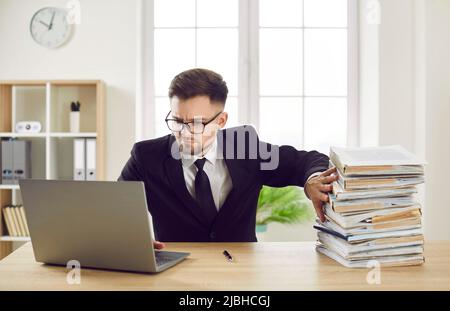 Bookkeeper does not like paper documents and works with digital files on laptop computer Stock Photo