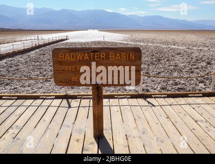 Wooden signpost of Badwater Basin with dry salt lake floor in the background. Death Valley National Park, California, USA. Steaming hot day in the Stock Photo