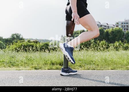 Sport man with prosthetic leg warming up before exercise workout training outdoor - Fitness disability concept - Focus on prosthesis Stock Photo