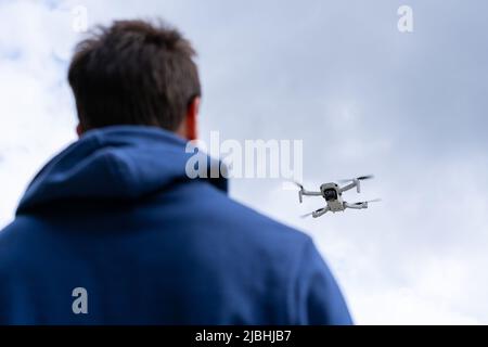 Young man with his back flying a drone outdoors Stock Photo