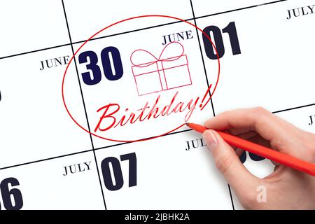 30th day of June. The hand circles the date on the calendar 30 June, draws a gift box and writes the text Birthday. Holiday. Summer month, day of the Stock Photo