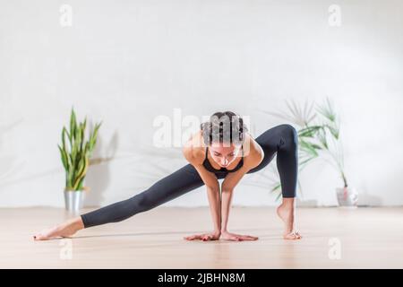 Barefoot elegant Caucasian ballerina doing stretching exercise standing on tiptoe in side lunge position looking at camera in studio Stock Photo