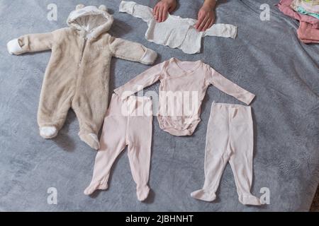 Baby's clothes laid out on bed, natural light Stock Photo