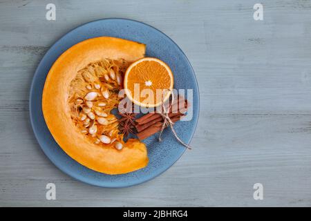 A fresh slice of pumpkin, oranges and spices on a blue plate on a light blue old wooden table. Jam ingredients. Top view Stock Photo