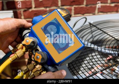 Male technician repairing outdoor air conditioner unit Stock Photo