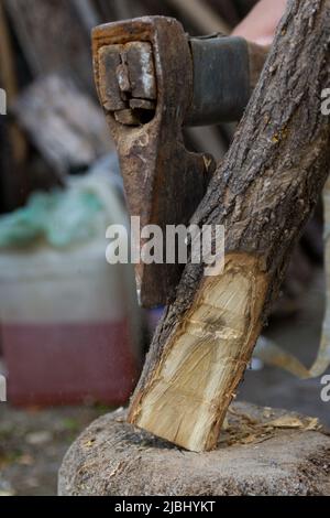 Process of sharpening wooden stick with an ax outdoor in a garden. Close up, selective focus Stock Photo