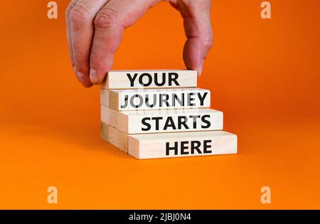 Your journey starts here symbol. Concept words Your journey starts here on wooden blocks on a beautiful orange table orange background. Business, moti Stock Photo