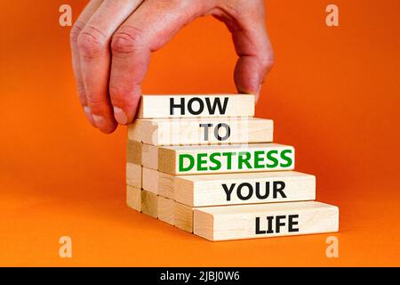 Destress your life symbol. Concept words How to destress your life on wooden blocks. Doctor hand. Beautiful orange background. Psychological business Stock Photo