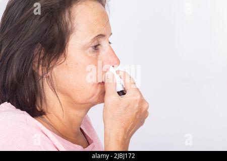 Side view of a woman using nasal spray - isolated. Stock Photo