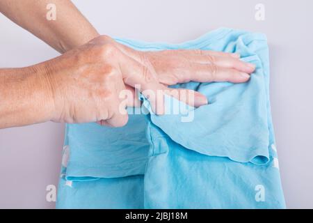 Close-up of woman's hands folding a t-shirt. Stock Photo