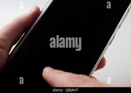 A woman holding and tapping the screen of a smartphone with the screen blacked out Stock Photo
