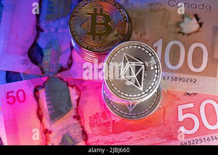 Toronto, Canada - October 30. 2021: Ethereum coin shining on top of Canadian Polymer Banknotes. Trading Cryptocurrency with CAD Dollars in Canada Stock Photo