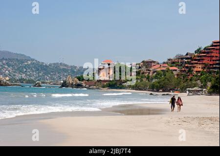 Couple strolling on the Playa Ropa beach in Zihuatanejo, Mexico Stock Photo