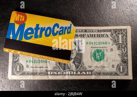 Manhattan, New York/USA - March 26. 2021: Metrocard on top of one dollar banknote. Purchasing a subway ticket in NYC Stock Photo