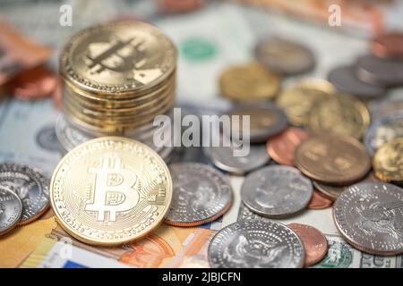 Bitcoins piled up on top of dollar and euro banknotes. Gold BTC coins with dollar coins, trading crypto concept Stock Photo