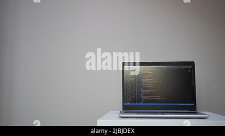 Opened laptop with code on the screen on the table Stock Photo