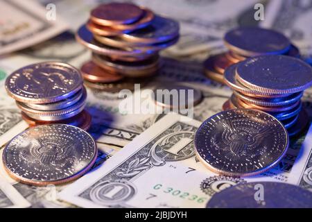 Piled up dollar coins on top of us dollar banknotes. Towering coins from pennies to half dollar coin Stock Photo