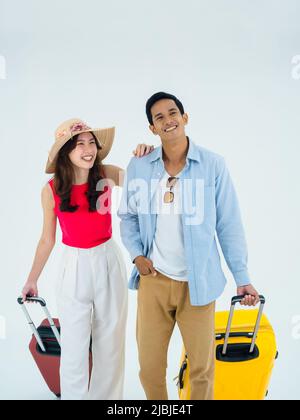 Couple travelers, happy holiday with friendships. Summer vacation. Young Asian man and woman in colorful costumes looks relax, walking with suitcases Stock Photo
