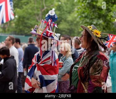 London, Greater London, England, June 04 2022: Jubilee Concert at The Mall. Lady draped in a union jack flag wears a teapot themed hat. Stock Photo