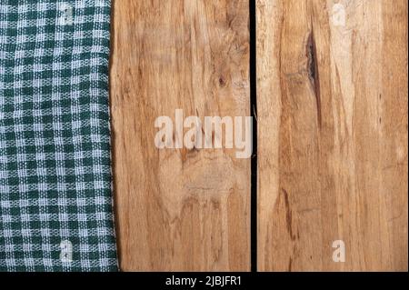 A green checkered cloth lies against a wooden background. A towel or kitchen napkin on the rough boards or kitchen table. Stock Photo