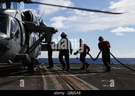 PHILIPPINE SEA (June 3, 2022) Sailors conduct a hot refueling on an MH-60S Sea Hawk helicopter, assigned to the “Chargers” of Helicopter Sea Combat Squadron (HSC) 14, aboard the Ticonderoga-class guided-missile cruiser USS Mobile Bay (CG 53). Abraham Lincoln Strike Group is on a scheduled deployment in the U.S. 7th Fleet area of operations to enhance interoperability through alliances and partnerships while serving as a ready-response force in support of a free and open Indo-Pacific region. (U.S. Navy photo by Mass Communication Specialist 3rd Class Alonzo Martin-Frazier) Stock Photo