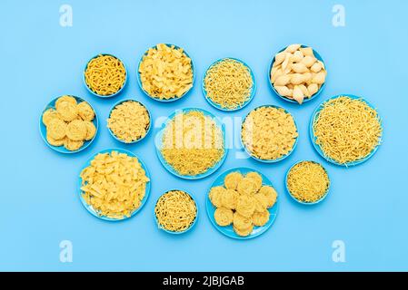 Top view with uncooked pasta of different types on a blue table. Various sorts of pasta in bowls and plates, on a blue background. Stock Photo