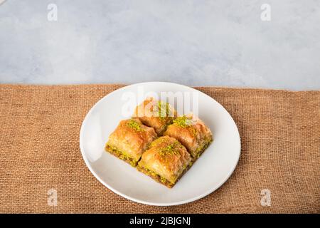 Traditional pistachio baklava in white plate.A plate baklava on burlap sack background Stock Photo