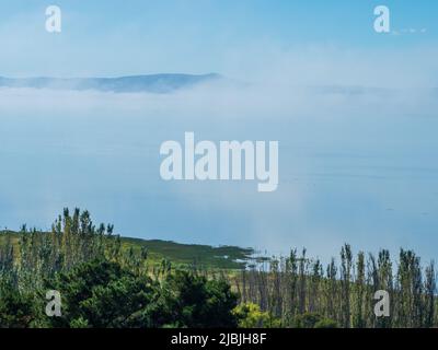 Looking down onto a misty cloudy Lake George, low clouds hiding most of the water,  from the lookout on a cool but sunny Autumn morning, NSW Australia Stock Photo