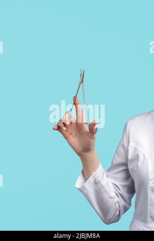 Faceless female surgeon holds needle holder in her hand. Doctor shows how to hold instrument correctly. Stock Photo