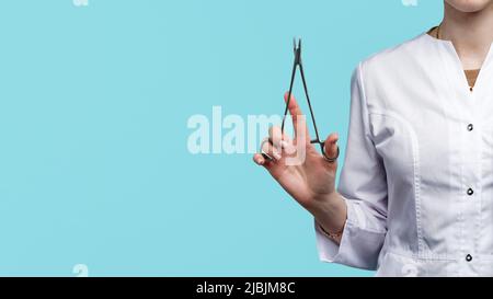 Unrecognizable female surgeon holds needle holder in her hand. Doctor shows how to hold instrument correctly. Stock Photo