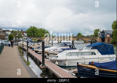 View along the river Thames towards Henley Bridge from Thameside footpath. Small leisure craft moored alongside the path. Henley on Thames, England. Stock Photo