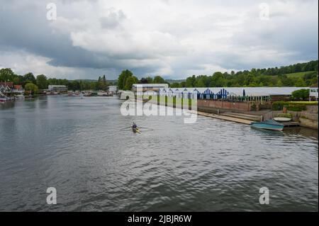 View along the River Thames from Henley Bridge on a dull, cloudy day. Rowers on the water in double scull. Henley on Thames, Oxfordshire, England, UK Stock Photo